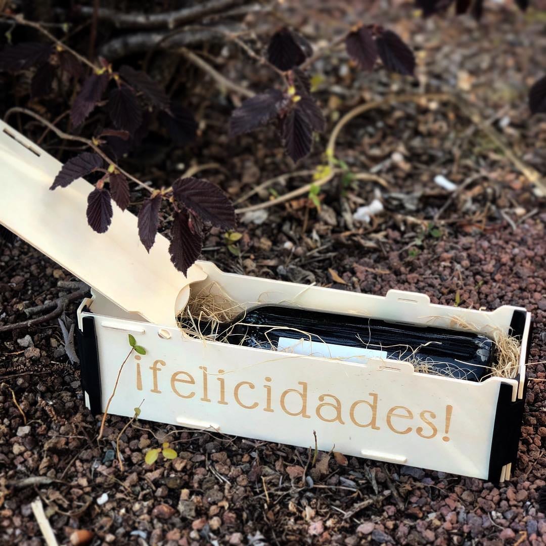 Caja de madera para una botella tumbada con «¡felicidades!» grabado en el frontal y la tapa entreabierta